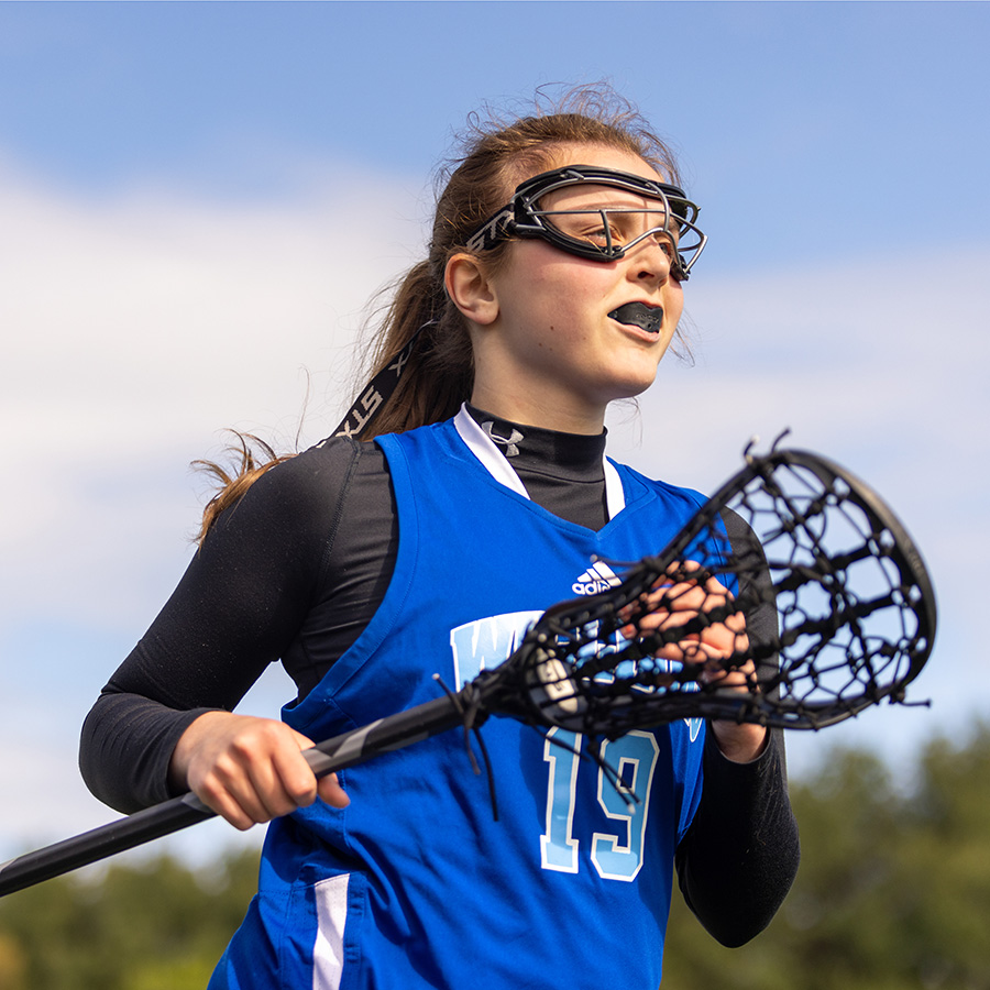 girl lacrosse player jogging with lacrosse stick