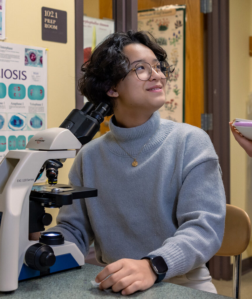 Williams School student sits at a desk with a microscope