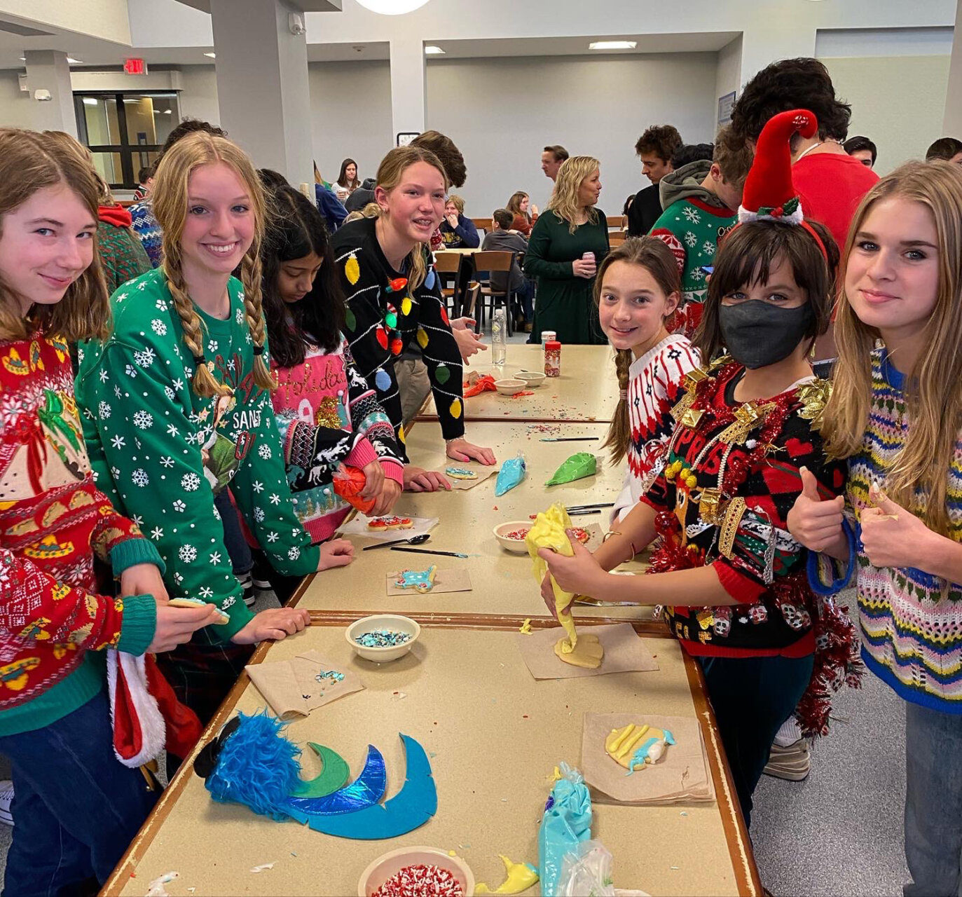 Williams School students decorating cookies during the holidays while wearing festive sweaters