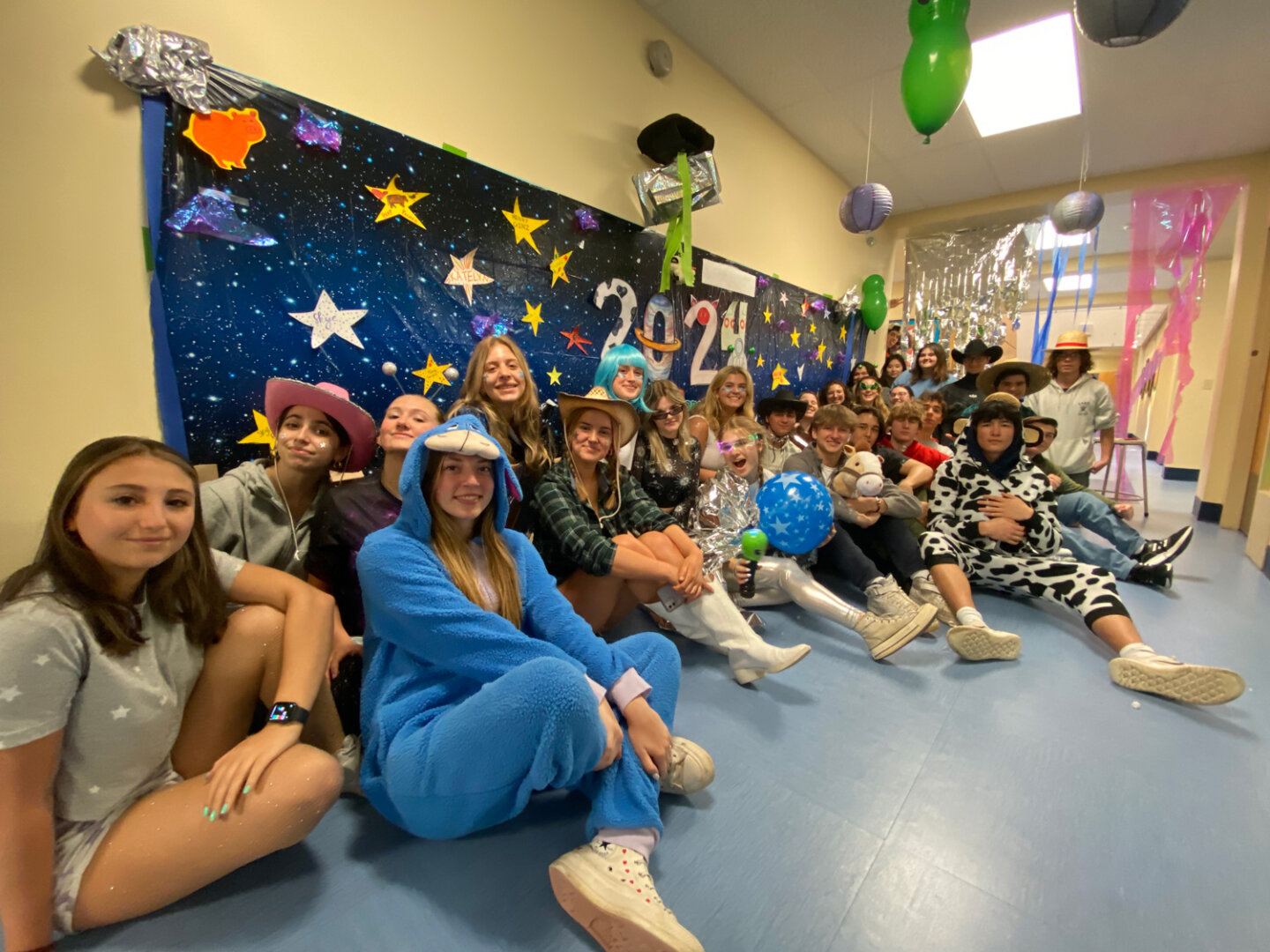 Williams School students sit on the floor in front of their 2024 mural during spirit week